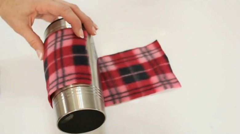 Hand wrapping metal thermos in black and red plaid scarf scrap