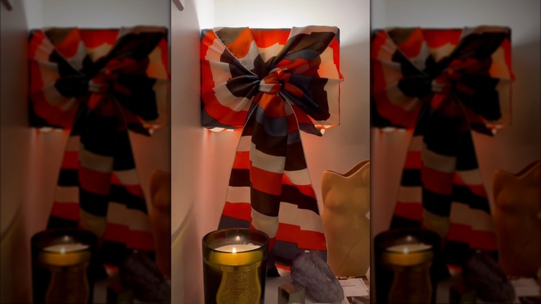Black, red, and white scarf tied around square lampshade in dimlit room