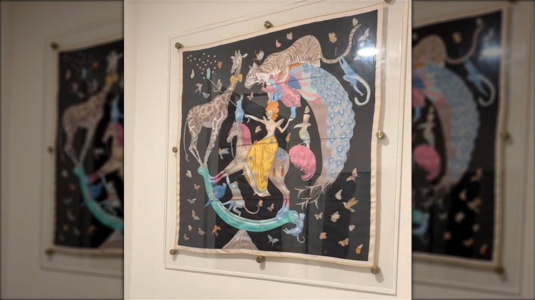 Designer Hermes scarf hanging in glass wall case in house