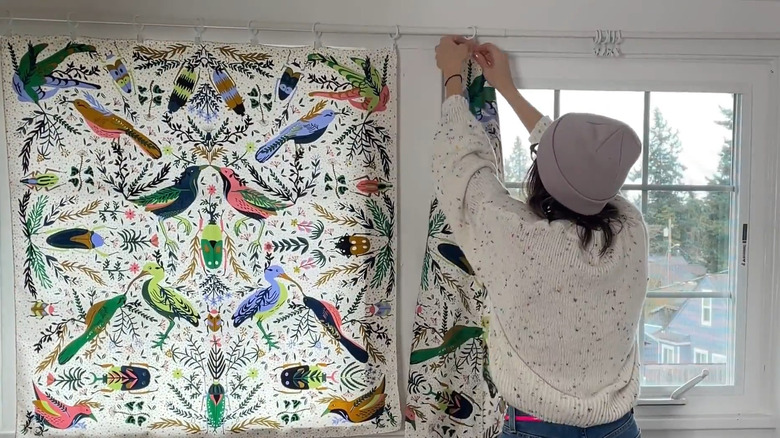 Bird and foliage scarf pinned on white rod over white windows