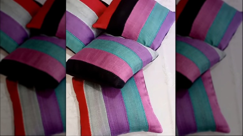 Striped scarves wrapped around throw pillows in heap on house floor