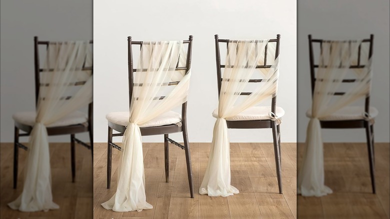 Wood dining chairs with sheer fabric tied across the back