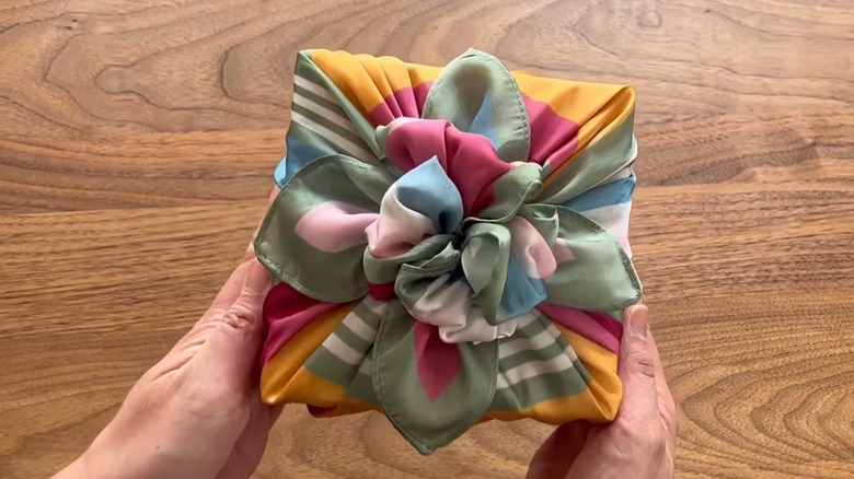 Brightly colored scarf tied into a bow and covering gift