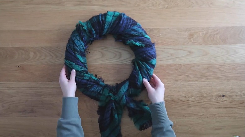 Round wreath form wrapped in a plaid green and blue scarf