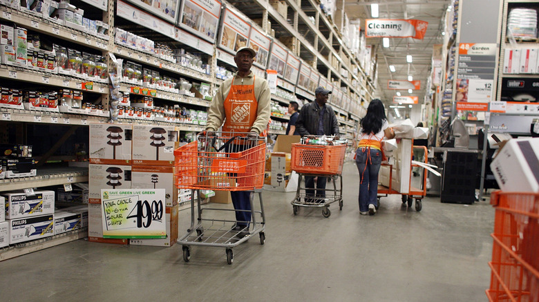 Shoppers and attendants walking with carts in a Home Depot