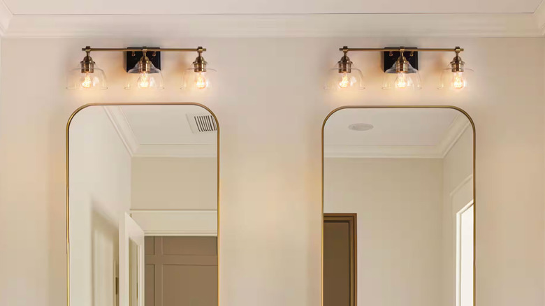 Two brass vanity lights hang over matching bathroom mirrors