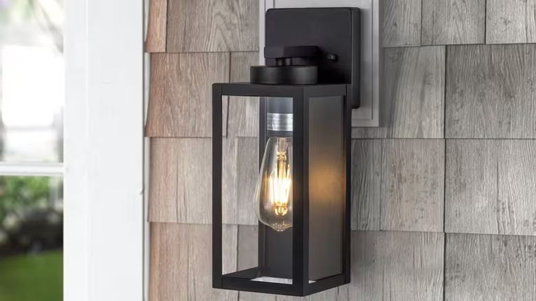 A modern one-light outdoor scone is installed on shake siding