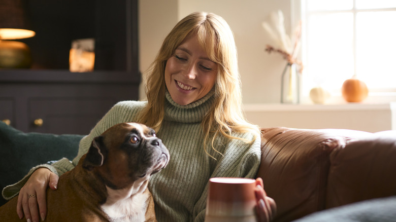 woman with cup of coffee and pet dog on a fall day