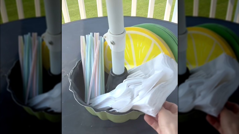 Rotating pan and umbrella on patio table with utensils, napkins, and plates
