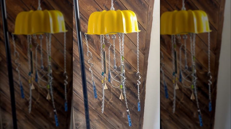 Hanging yellow Bundt pan with chains, chimes, and bells outdoors
