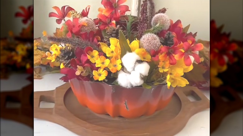 Ombre cake pan with fluted sides atop cutting board with fall florals