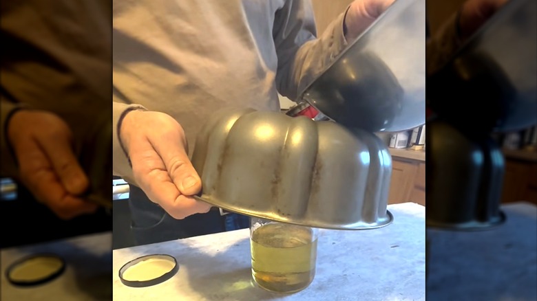 Person using Bundt cake pan as funnel to pour oil into glass