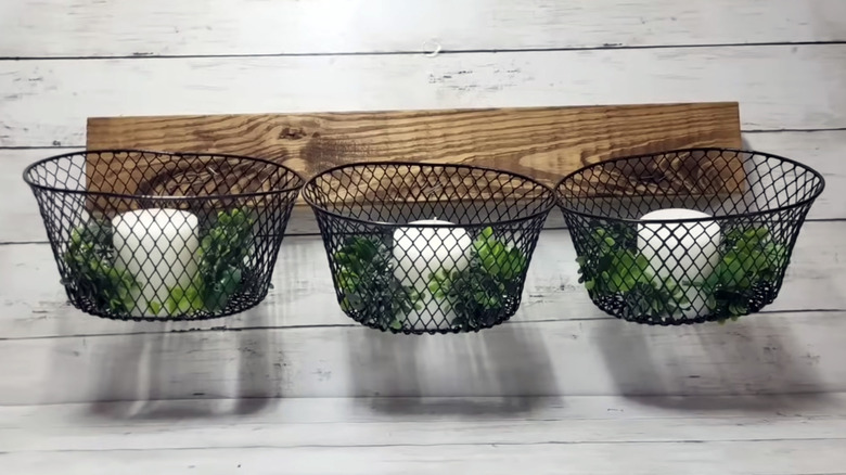 A three wire basket display holds white candles and greenery