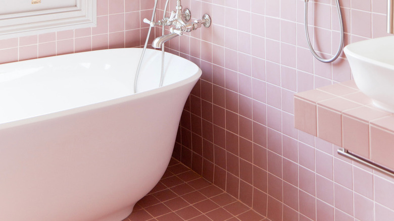 pink bathroom with freestanding bathtub and exposed plumbing