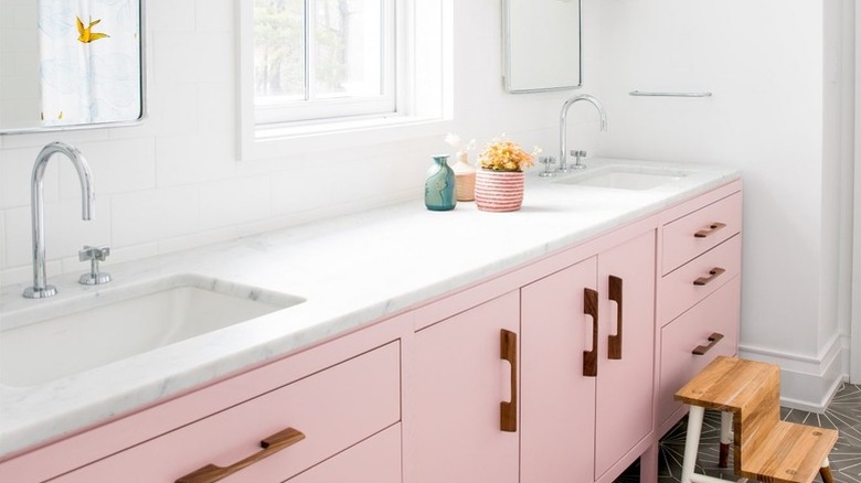 A bathroom with pink cabinetry