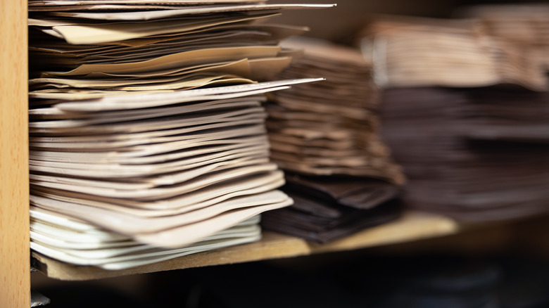Stacks of papers sit on a wooden bookshelf