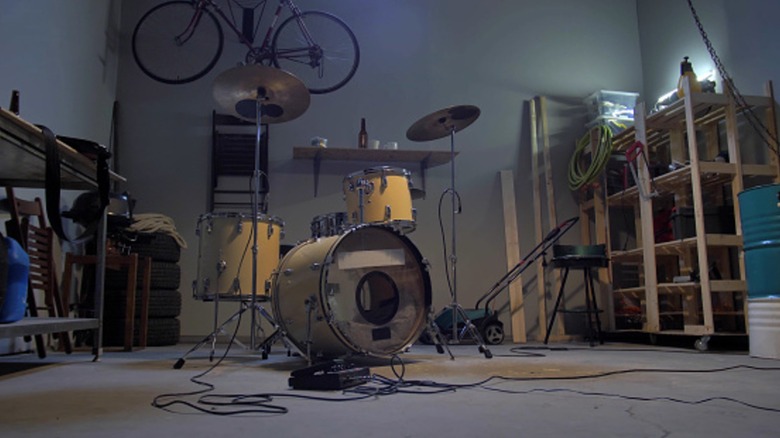 A drum set sits on a cluttered garage floor