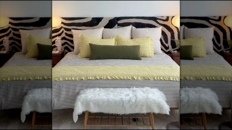A bed with white yellow and green sheets and a zebra headboard