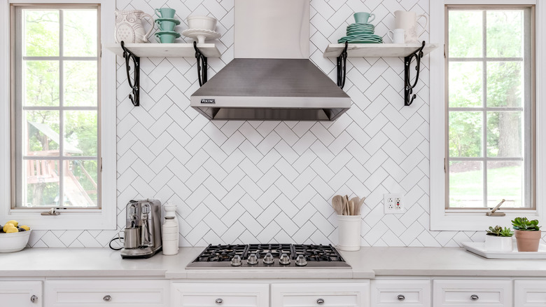 A kitchen with a white herringbone subway tile backsplash