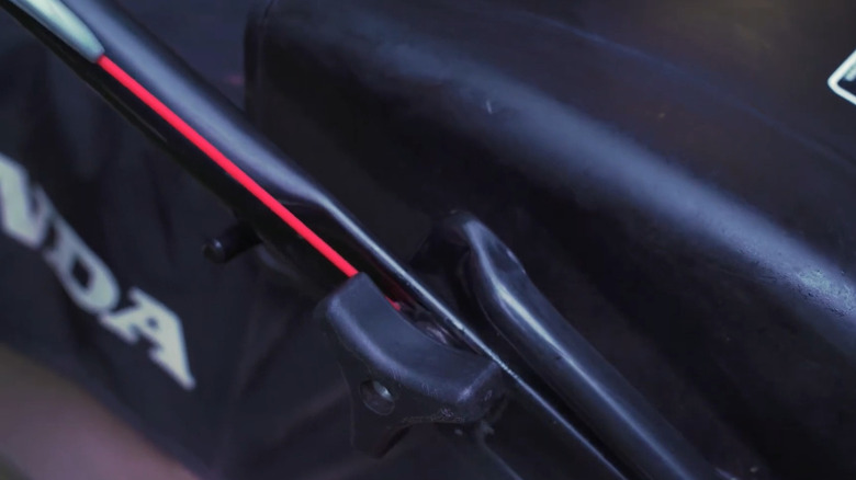 Spraying a mower bolt with WD-40
