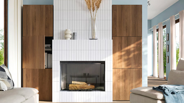 Two walnut BESTÅ Storage cabinets flank a modern white tiled fireplace