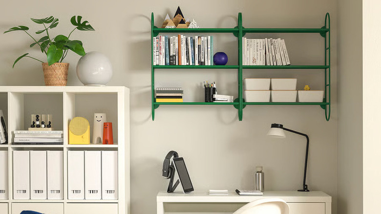 A green FÄRGSÄTTARE Wall shelf from IKEA hangs on a wall above a white desk