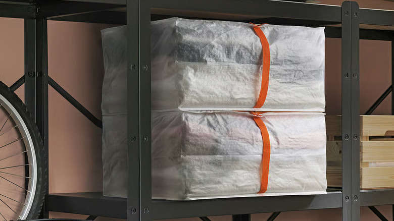 Two white PÄRKLA Storage cases from IKEA sit on a black metal shelf in a garage