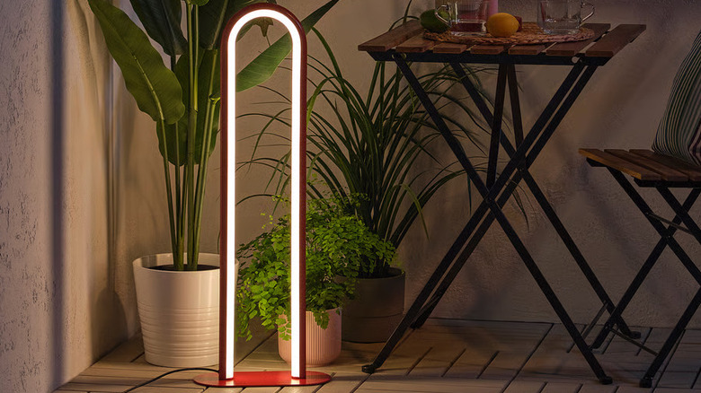 A modern SOLVINDEN Floor lamp sits on the floor next to a cafe table