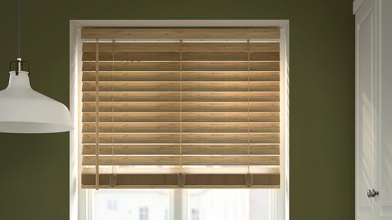 A bamboo VECKLARFLY Venetian blind from IKEA is installed on a window flanked by a white pendant light and white cabinet