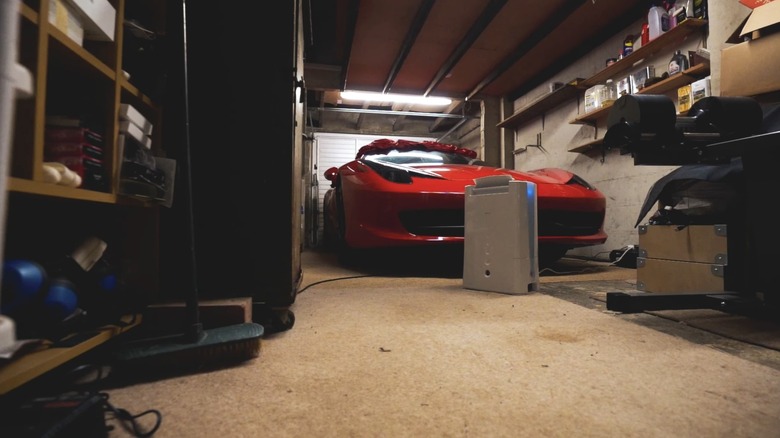 A dehumidifier running in a garage with a red luxury car and tools