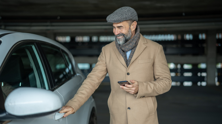Man standing by a car with a smartphone