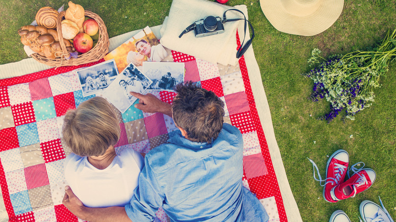 Couple looking at photos spread on a patchwork picnic blanket