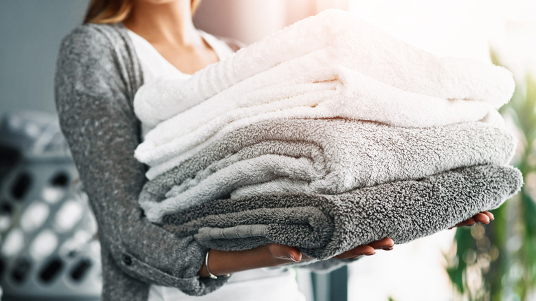 a woman carries a stack of gray and white towels