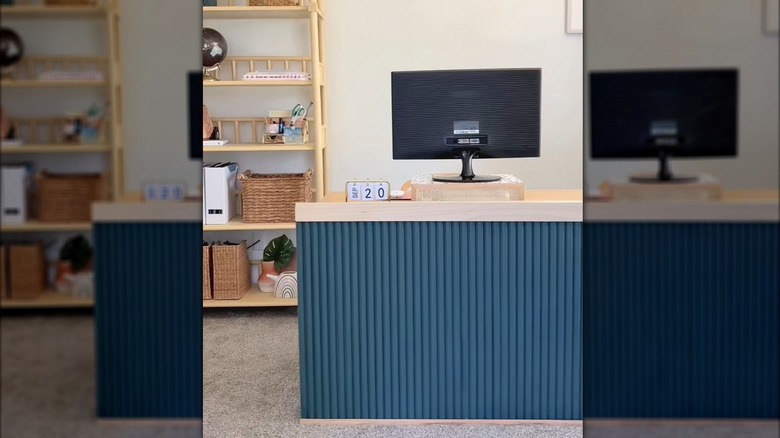 Modern home office desk with DIY blue fluted paneling beside neutral colored shelf and decor
