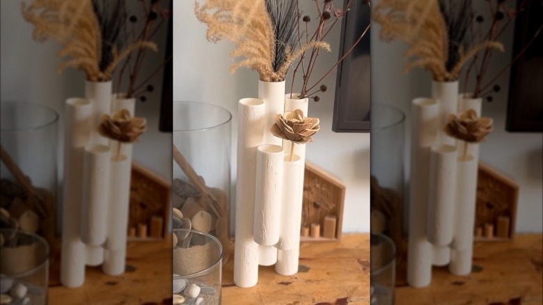 White textured vase made of multiple staggered PVC pipes with dried foliage decor