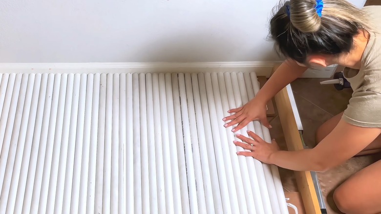 Woman working with many narrow PVC pipes on floor for home project