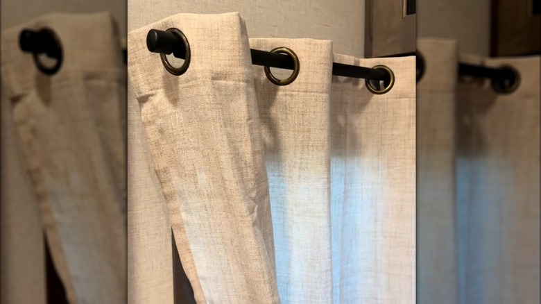 Close-up of black curtain rod with hanging linen curtains