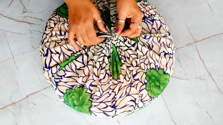 Woman repurposing T-shirts into stylish round couch cushion