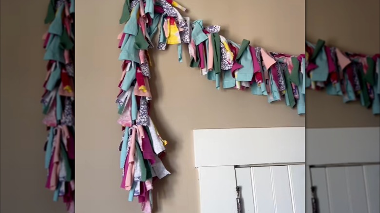 Hanging multicolored tassel made from scrap clothing over white panel door