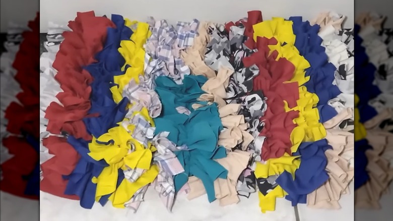 Ruffled clothing pieces combined into cozy, eccentric floor rug