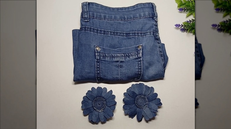 Denim jeans beside denim flower DIY project on white surface