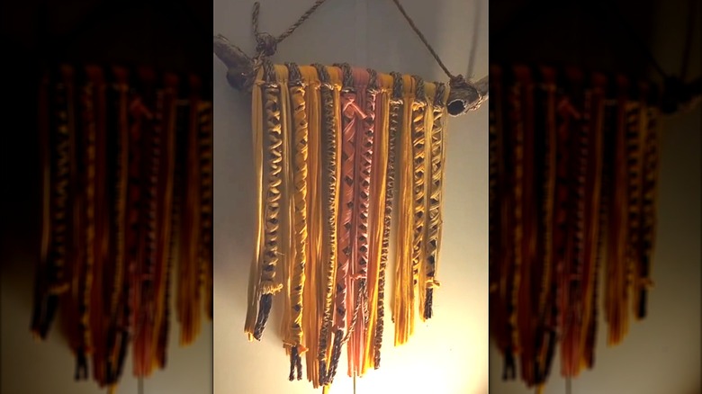 Bohemian-style macrame hanger made with rustic wood, rope, and torn clothing pieces