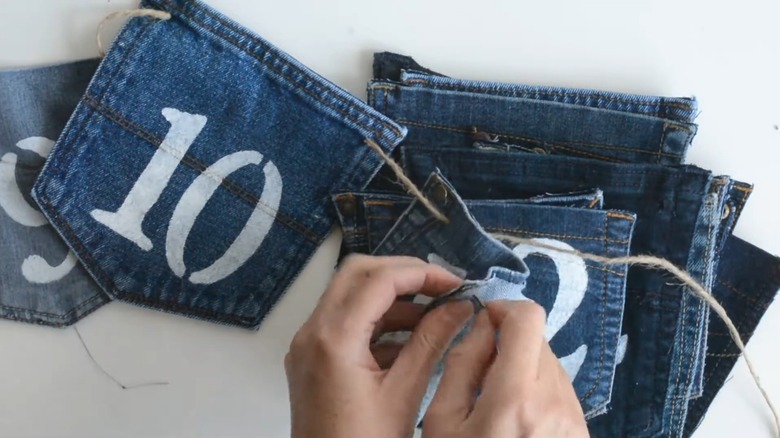 Woman sewing jean pockets together with numbers on piece of twine