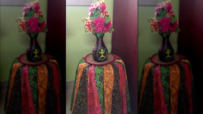 Colorful skirt being used as end tablecloth with unique vase and flowers