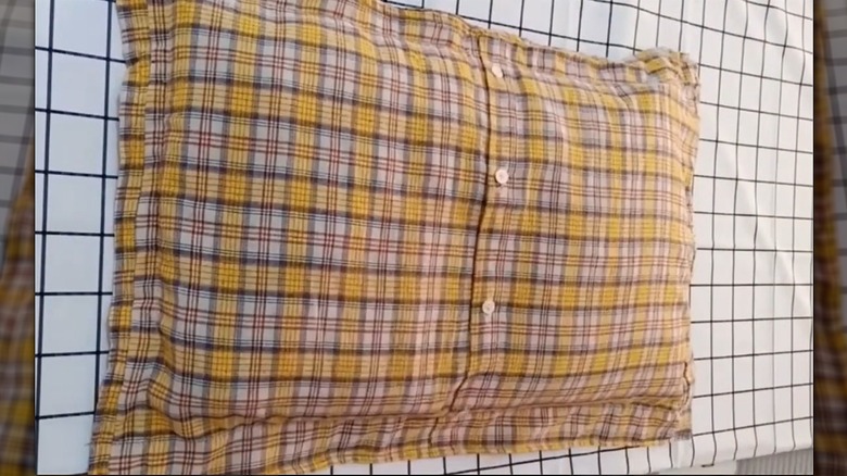 Flannel shirt transformed into pillow with button closure on grid surface
