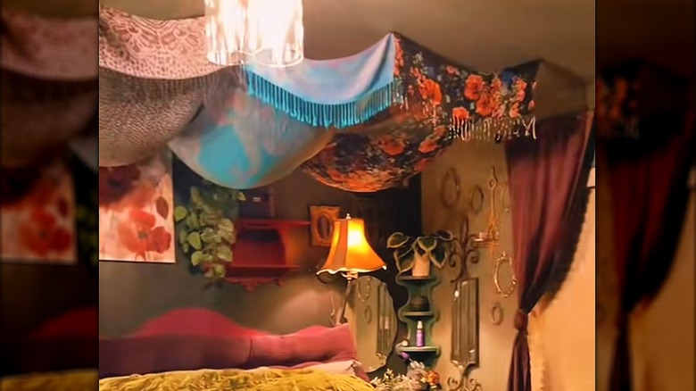Colorful pashminas hanging above bed in eccentric, boho bedroom