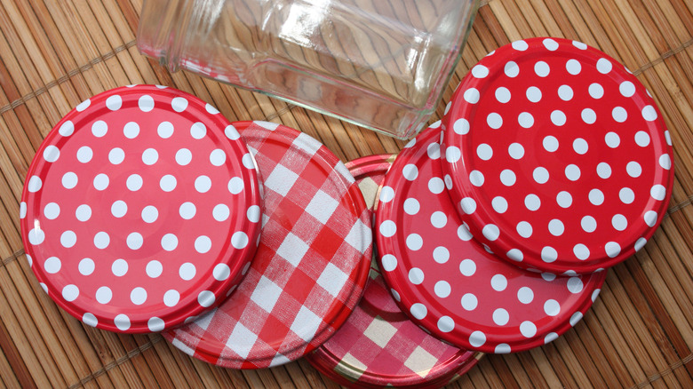 Red-and-white lids beside an empty jam jar