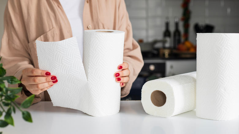 A person tearing a paper towel off a roll in a kitchen