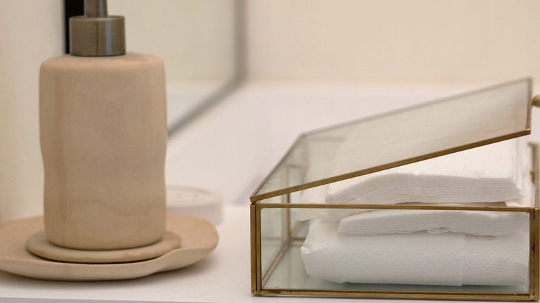 Glass storage box on bathroom counter with extra hand towels.
