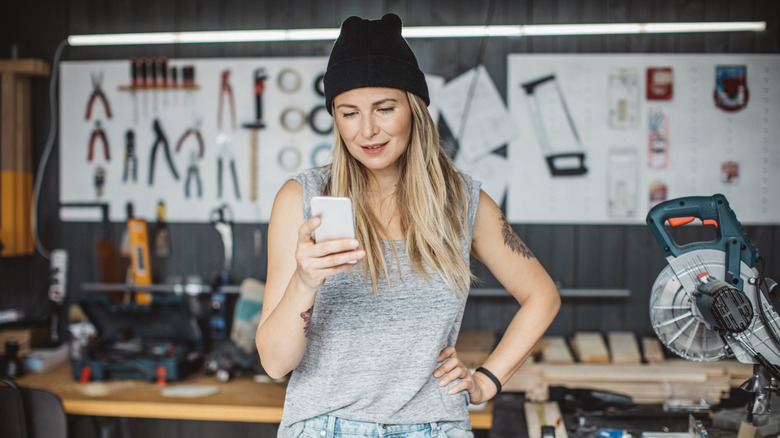 Woman looking at her phone while standing in her garage